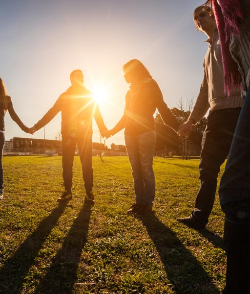 Group of friends holding hands outdoors at sunset