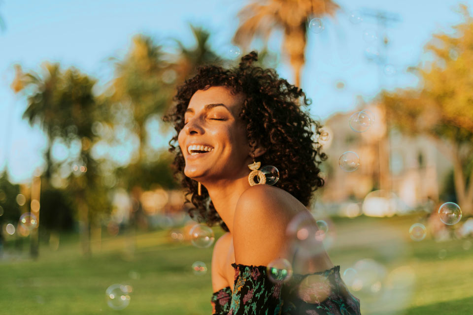 Stylish Latina woman smiling outdoors with bubbles around her