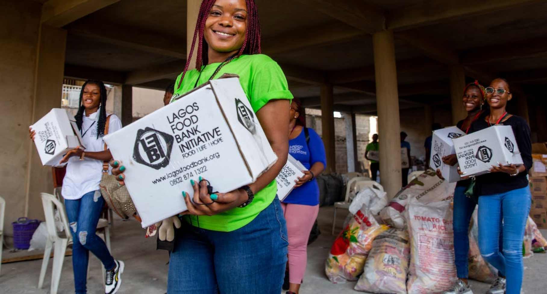 Young woman smiling while holding a food drive box