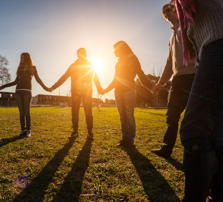 Group of friends holding hands outdoors at sunset